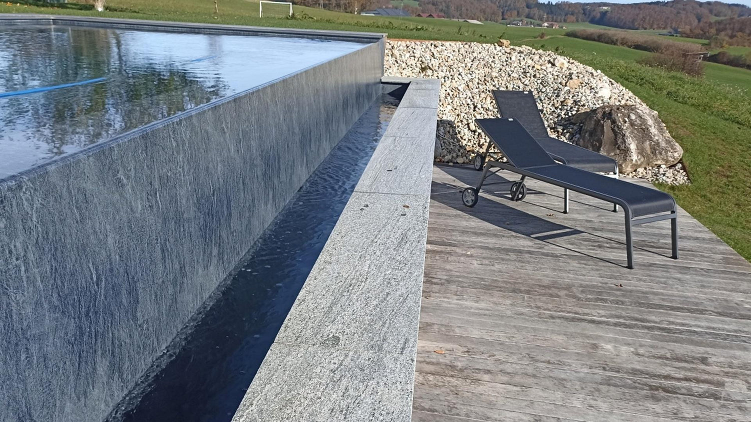 Moderner Überlaufpool mit Gneis-Abdeckplatte